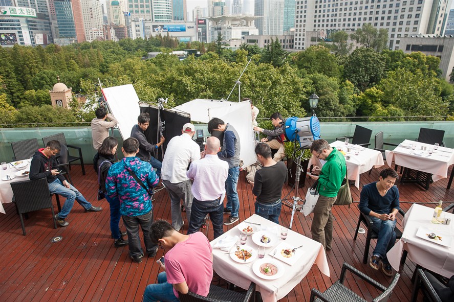 Shenzhen production crew reviewing a shoot on location with city buildings in the background